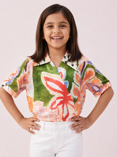 Young girl wearing a colorful floral shirt with a plain background