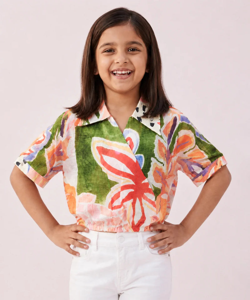 Young girl wearing a colorful floral shirt with a plain background
