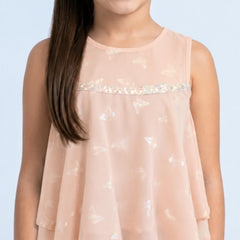 Young girl wearing a light pink sleeveless top with sequin details on a light blue background
