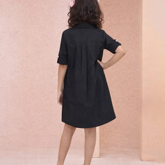 Woman wearing a black dress against a pink wall