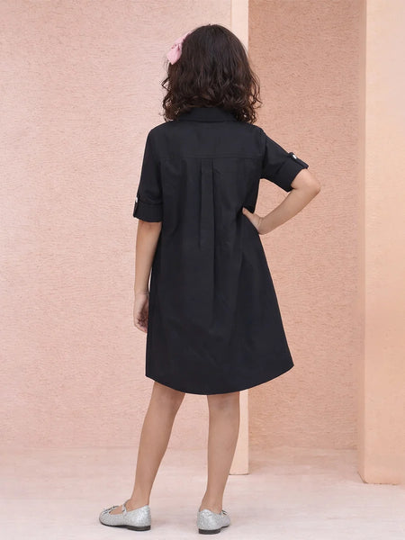 Woman wearing a black dress against a pink wall