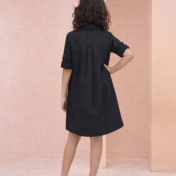 Woman wearing a black dress against a pink wall