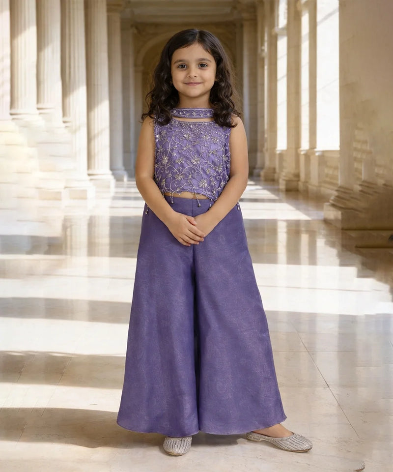 Young girl in a purple outfit standing in a sunlit hallway with columns.