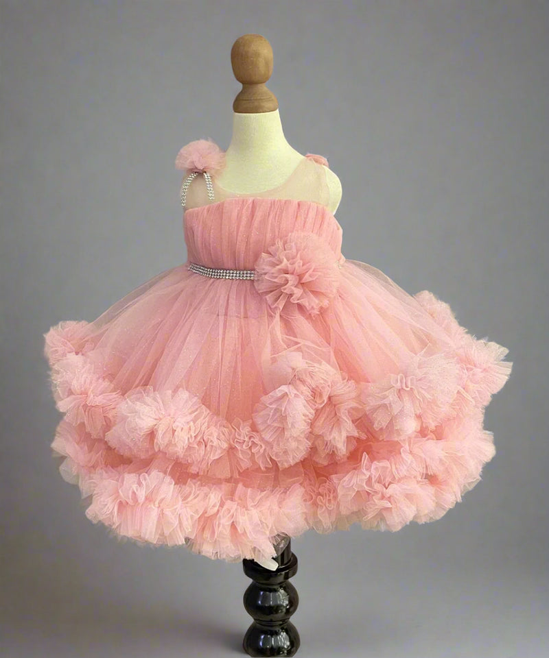 Pink Colored birthday wear frock that comes with a fancy belt attached on the waist and a beautiful floral detailing. 