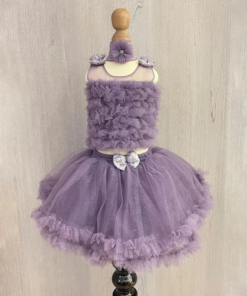  It's a purple Colored shimmer crop-top skirt set that comes with a back hook closure. Moreover, it comes with a matching shoes and hair accessory.