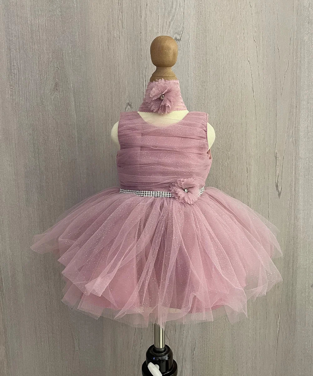 It's a onion pink Colored shimmer frock that comes with a back hook closure. It is paired up with a matching shoes and hair band.