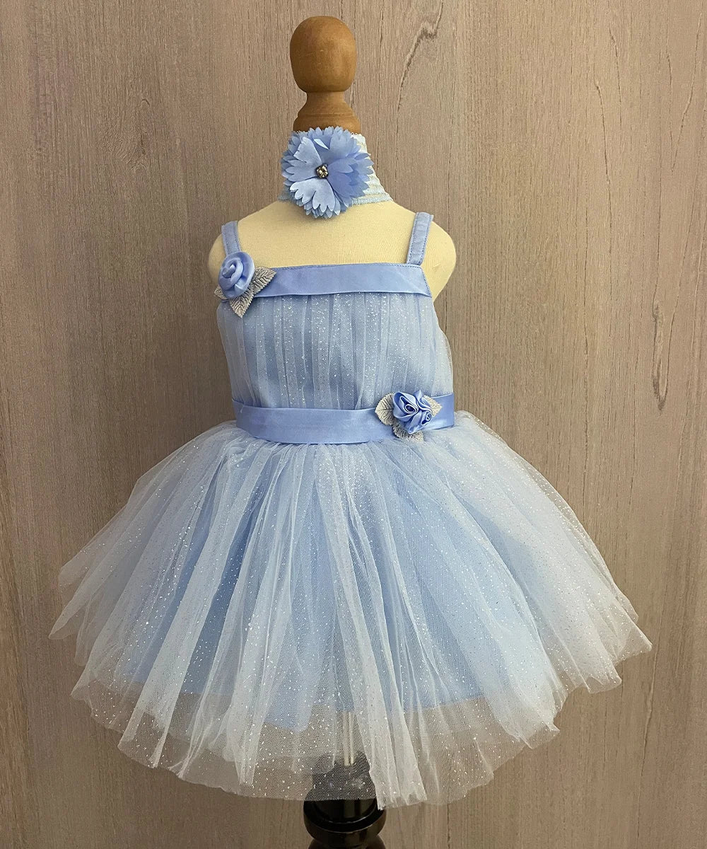 It is a sky blue shimmer frock with a back zip closure and comes with matching shoes and a hairband. It features cute flowers and ribbon detailing and an attached fabric belt to be tied at the back.