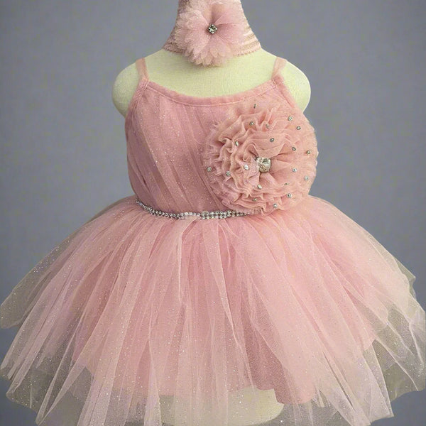 It's a peach Colored frock that features shinny lace, big flower and pleated detailing. Moreover, it comes with an attached belt to be tied at the back.