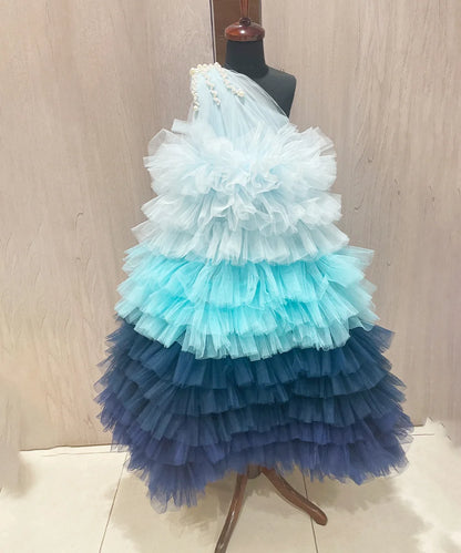 It’s a blue shaded ruffle gown, a perfect children birthday dress as well as girls wedding outfit. It features a beautiful pearl detailing on the shoulder that uplifts the entire look.
