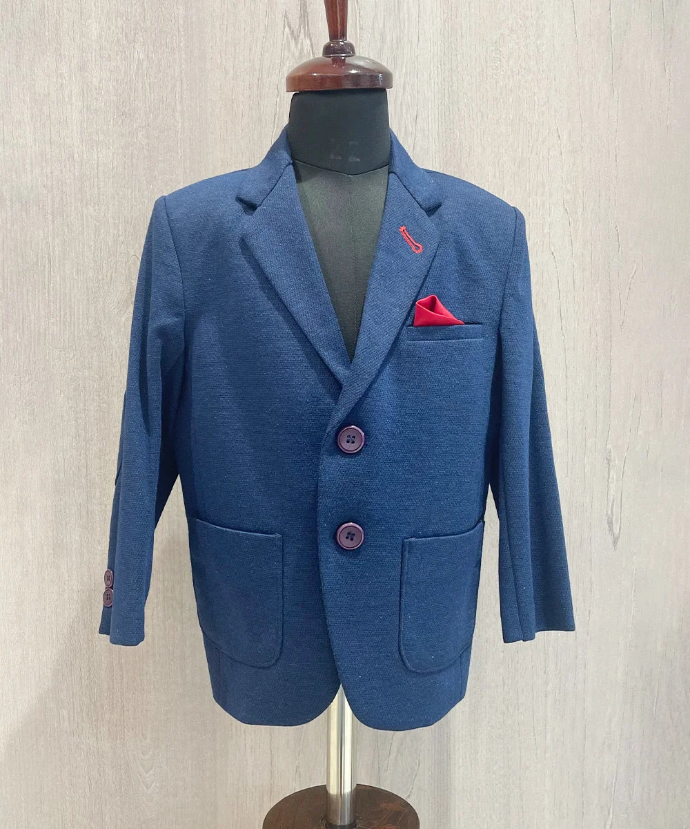 It’s a navy blue Colored boys wedding wear blazer that comes with a red pocket square. It features elbow patch detailing on sleeves.