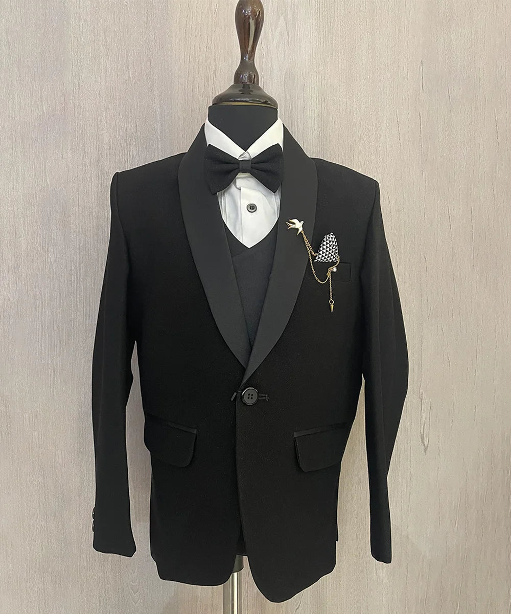 This boys wedding outfit consists of a black Colored shimmer coat, waistcoat, matching pants and a white Colored shirt that comes with pin tucks detailing on it. It features a matching shimmer bow, a broach and a printed pocket square that uplifts the entire look.