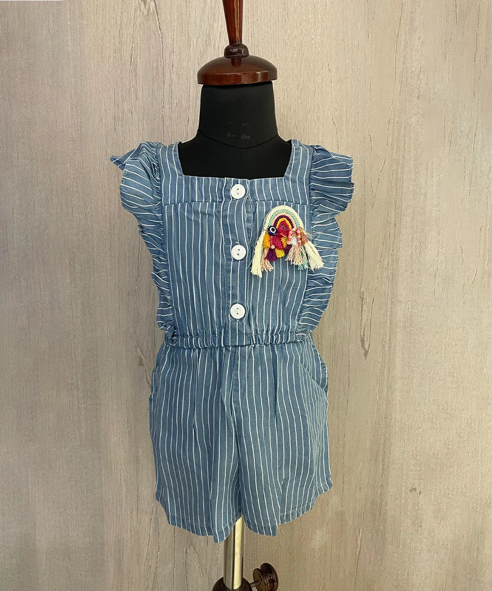  It's a blue colored jumpsuit that comes with an elasticated waist. There is a patchwork of rainbow and some frill detailing too. Moreover, there are 4 pockets on the dress.