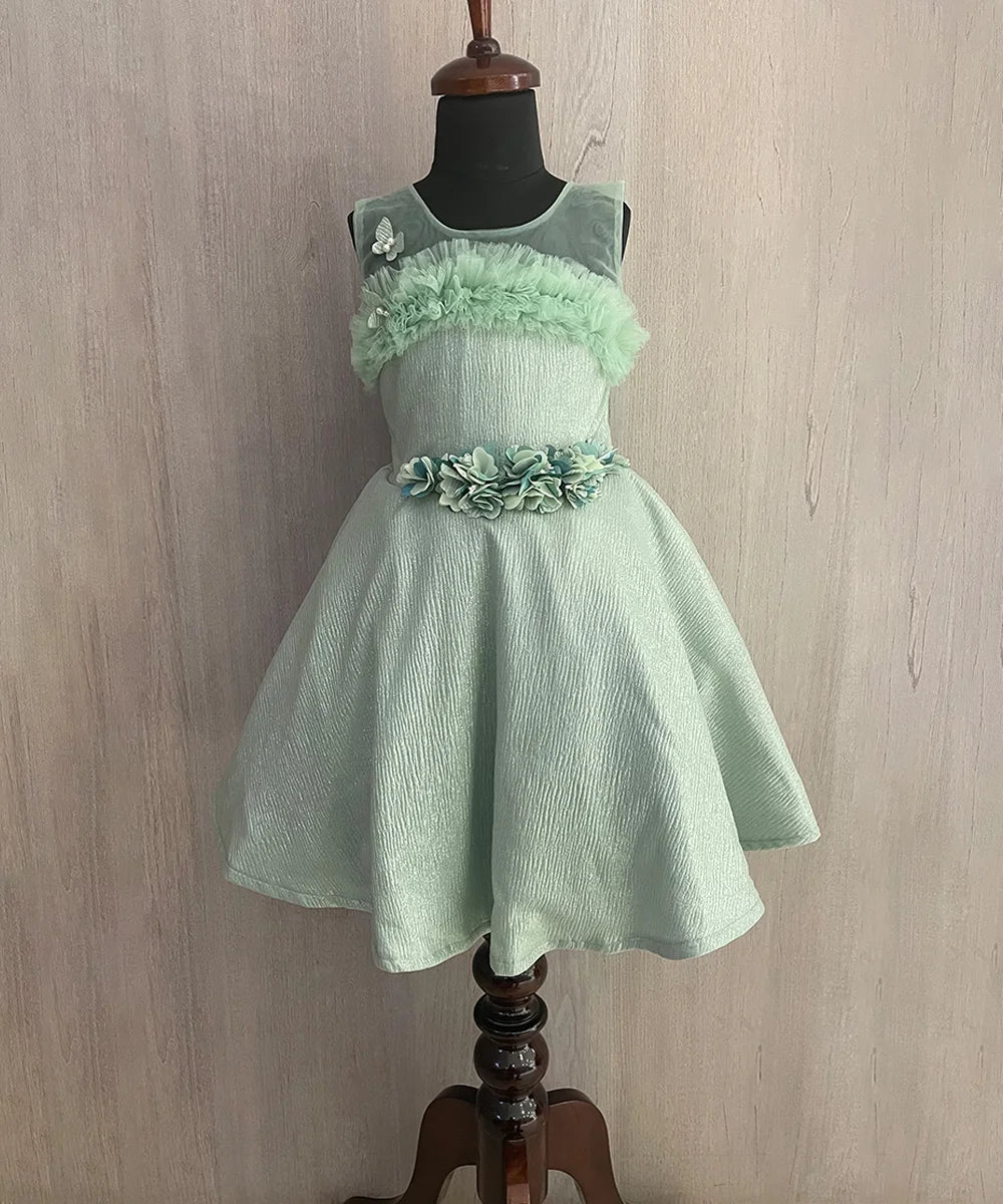  It’s a Pista green Colored shimmery western outfit for kids with a back zip closure and some frilly detailing. It features a cute butterfly and floral detailing.