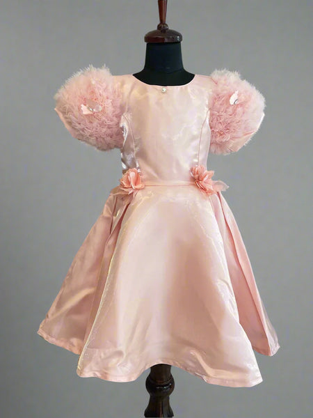 This is a beautiful peach colored kids birthday wear frock for little girls. It features cute floral detailing on the waist. Moreover, it features a pearl detailing that adds grace to the look.