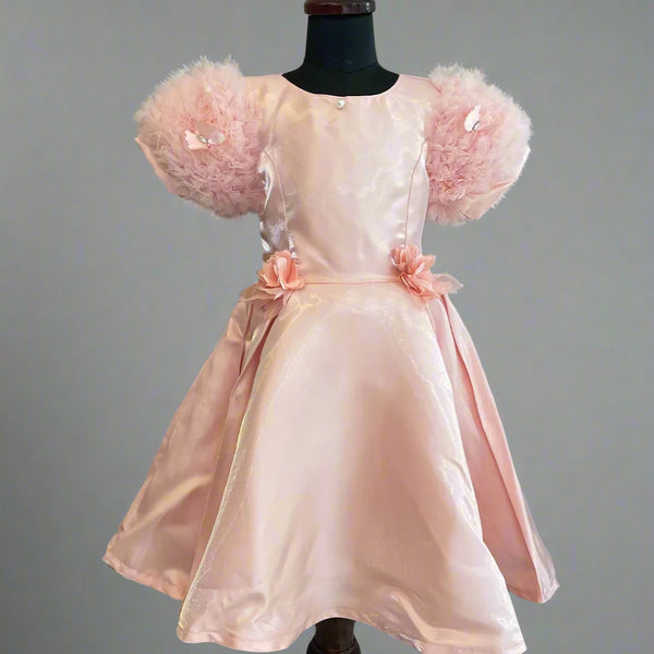 This is a beautiful peach colored kids birthday wear frock for little girls. It features cute floral detailing on the waist. Moreover, it features a pearl detailing that adds grace to the look.