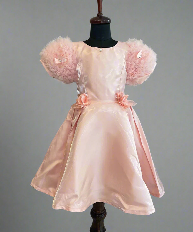 This is a beautiful peach colored kids birthday wear frock for little girls. It features cute floral detailing on the waist. Moreover, it features a pearl detailing that adds grace to the look.