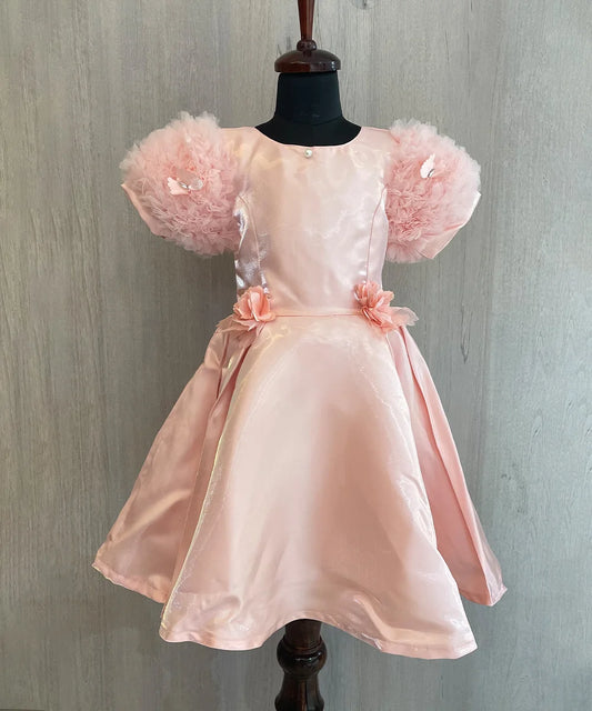 This is a beautiful peach colored kids birthday wear frock for little girls. It features cute floral detailing on the waist. Moreover, it features a pearl detailing that adds grace to the look.