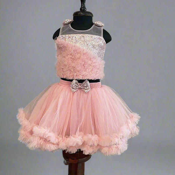 This pink colored dress consists of a fancy crop top that comes with a back hook closure and a layered ruffle skirt. It is paired up with a matching handbag, shoes and hairband. It features bow detailing on the shoulder and on the waist.
