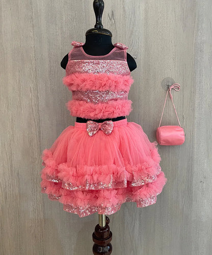  This  pink dress consists of a crop top that comes with a back hook closure and a layered skirt. It is paired up with a matching handbag. It features bow detailing on the shoulder and on the waist. Moreover, there are frill detailings on the dress that elevates the whole look.