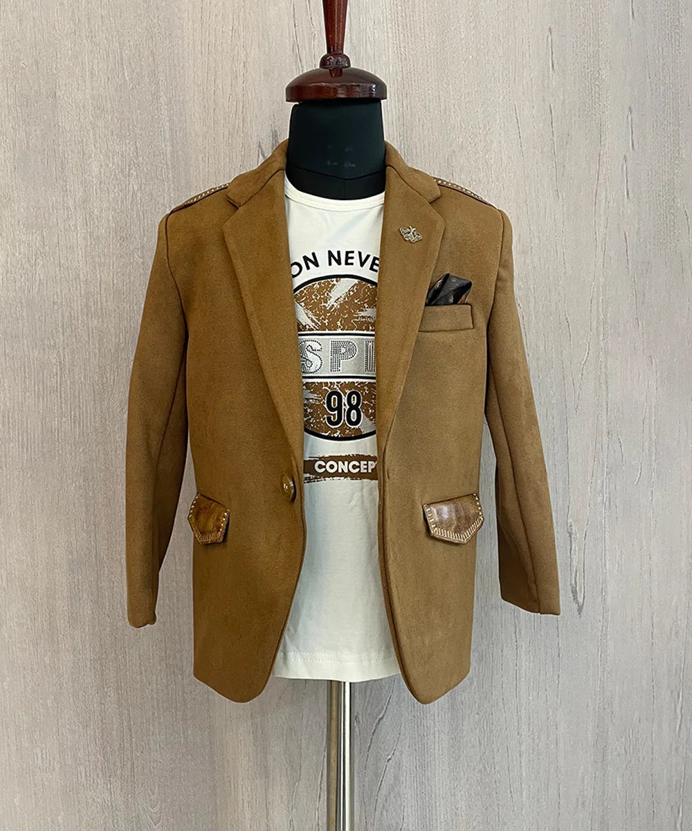 This boys wedding outfit consists of a Tan Brown Colored Blazer and a matching self-printed white Colored t-shirt. It features a cute broach, a printed pocket square and leather detailing on the blazer that adds to the look.