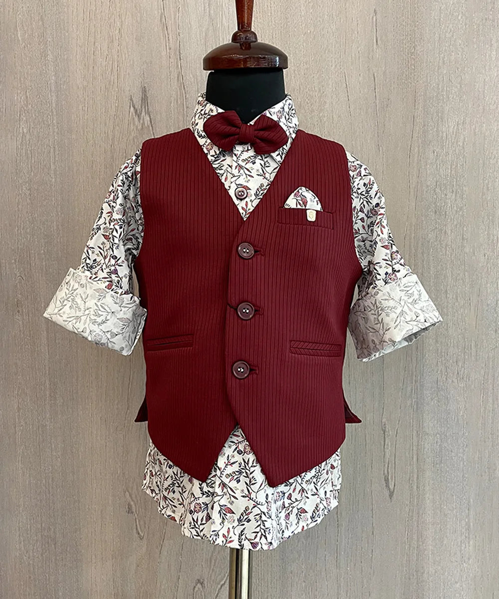 This wedding dress for small boy consists of a maroon Coloured waistcoat, matching pants and a self-printed white Coloured shirt. It features a matching bow, a cute broach and a printed pocket square.