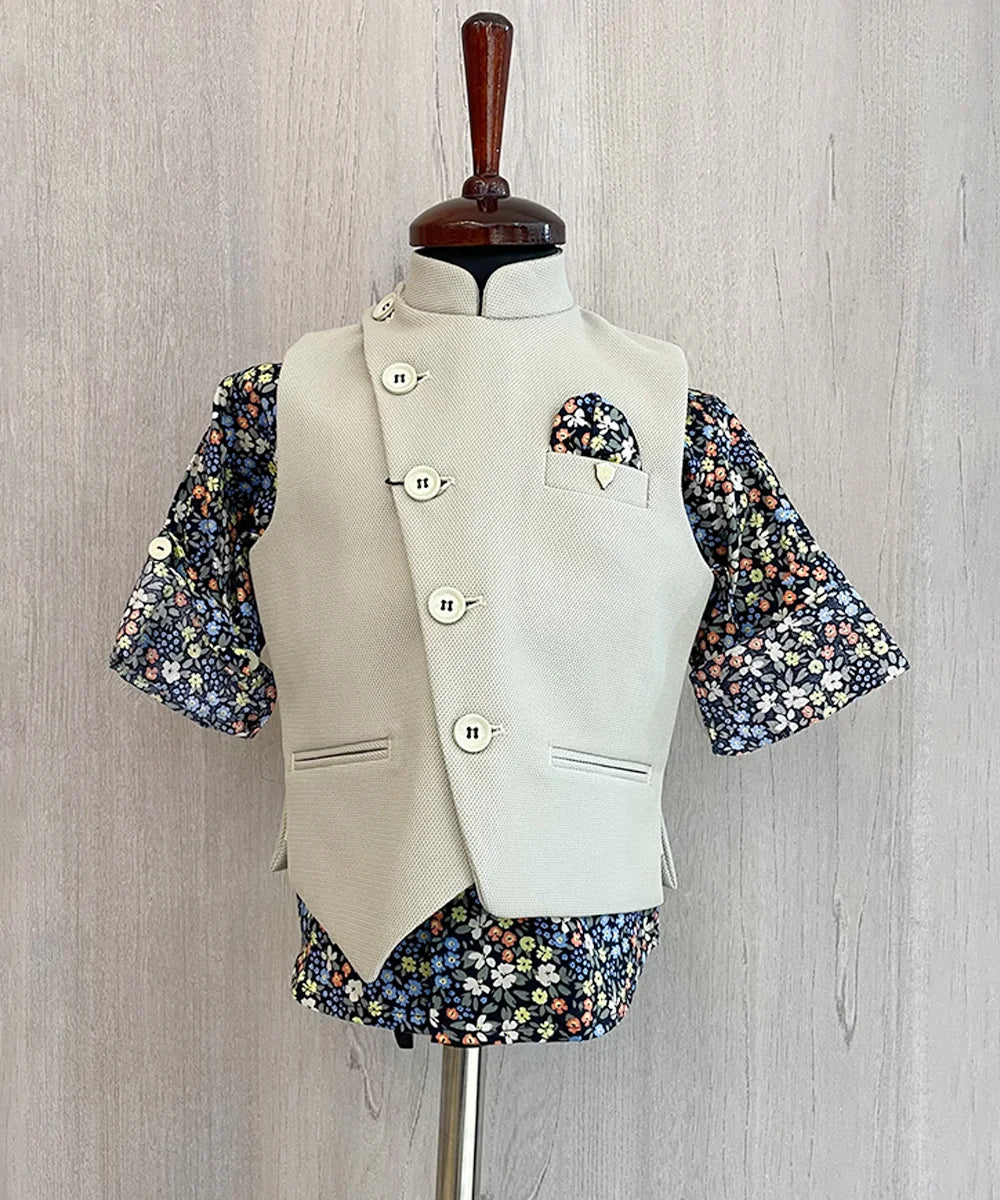 This boys party clothes set consists of a cream coloured waistcoat, matching pants and a self-printed blue Coloured shirt. It features a cute broach and a printed pocket square that uplifts the entire look.
