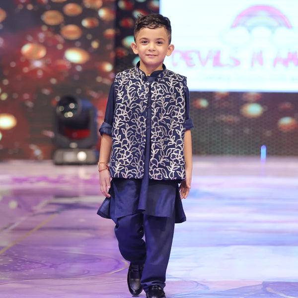 Child wearing a navy blue color kurta pyjama with a nehru jacket with shimmer work.