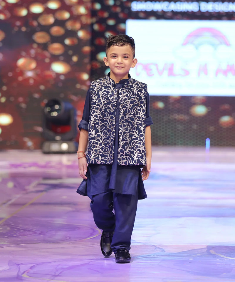 Child wearing a navy blue color kurta pyjama with a nehru jacket with shimmer work.