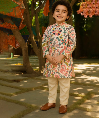 Child wearing a floral kurta with beige pants standing outdoors.