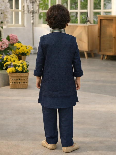 Child wearing a navy blue traditional outfit standing in a room with flowers and furniture.