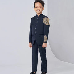 Child wearing a formal black suit with gold accents on a white background