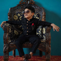 It is a beautiful full black self-Jacquard design Jodhpuri Suit for Boys. It consists of a Jodhpuri Coat along with matching pants, a broach and a red coloured pocket square.