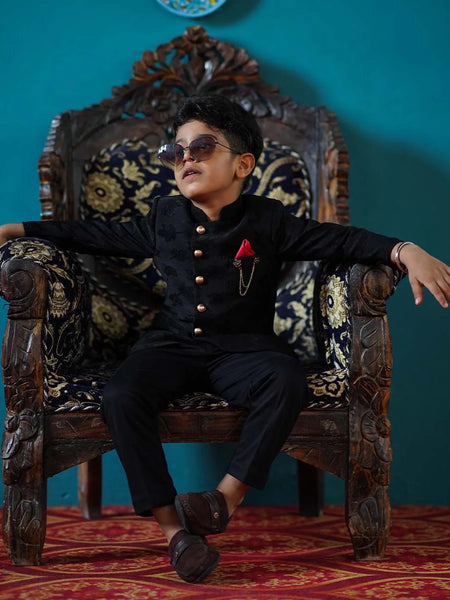 It is a beautiful full black self-Jacquard design Jodhpuri Suit for Boys. It consists of a Jodhpuri Coat along with matching pants, a broach and a red coloured pocket square.