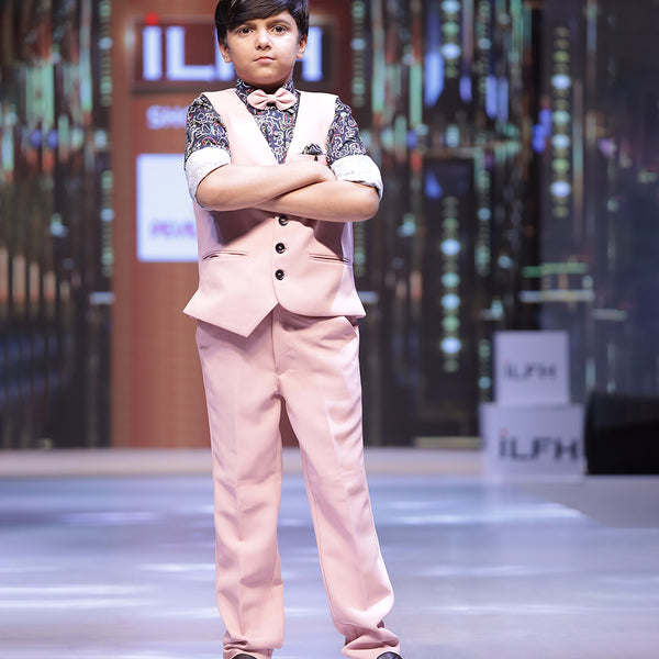This boys party clothes set consists of a light pink Coloured waistcoat, matching pants and a self-printed shirt. It features a matching bow, a cute broach and a printed pocket square that uplifts the entire look.