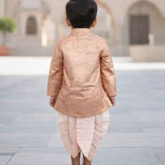 Child wearing a traditional outfit standing in an outdoor setting with arches in the background.