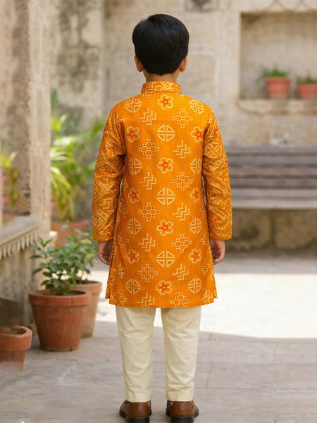 Child wearing a traditional orange kurta with white pants in an outdoor setting.