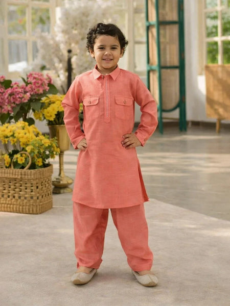 Child wearing a coral traditional outfit standing in a room with flowers and furniture.