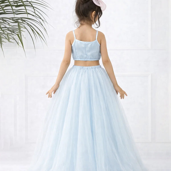 Young girl wearing a light blue two-piece dress with a white background