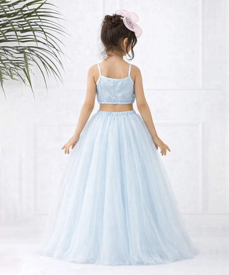 Young girl wearing a light blue two-piece dress with a white background