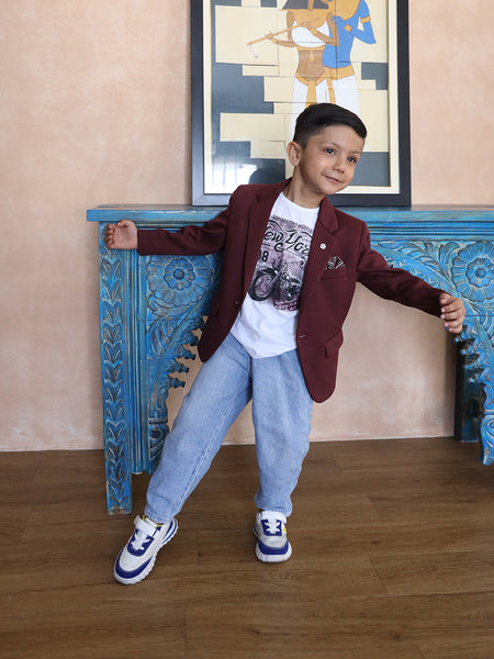 This boys wedding outfit consists of a Maroon Colored Blazer and a matching self-printed white Colored t-shirt. It features a small broach, a printed pocket square and elbow patch detailing that uplifts the entire look.