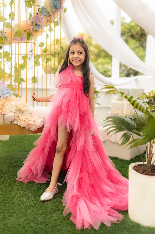  It is a pink coloured designer up-and-down birthday girl gown that comes with a frill and big bow detailing on the shoulder.