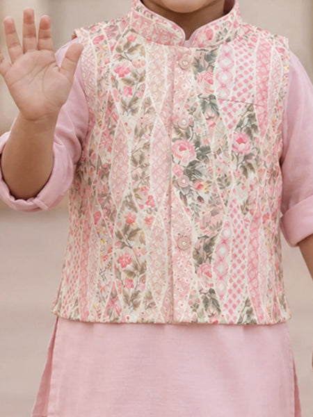 A child wearing a pink traditional outfit with a patterned vest featuring pink floral and geometric designs, set against a soft beige background.
