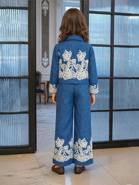 Person wearing a blue outfit with white floral embroidery in an indoor setting.
