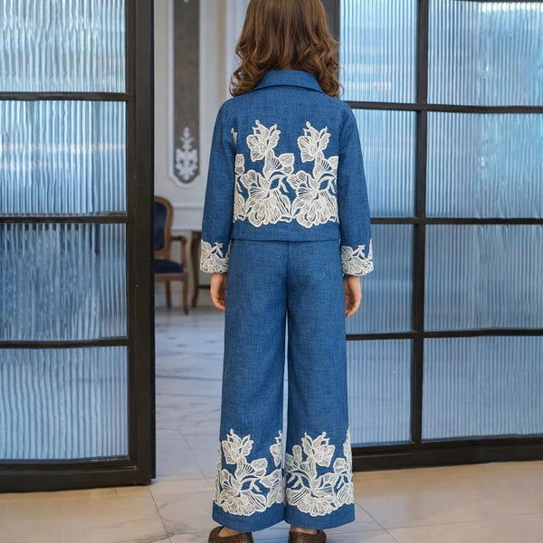 Person wearing a blue outfit with white floral embroidery in an indoor setting.