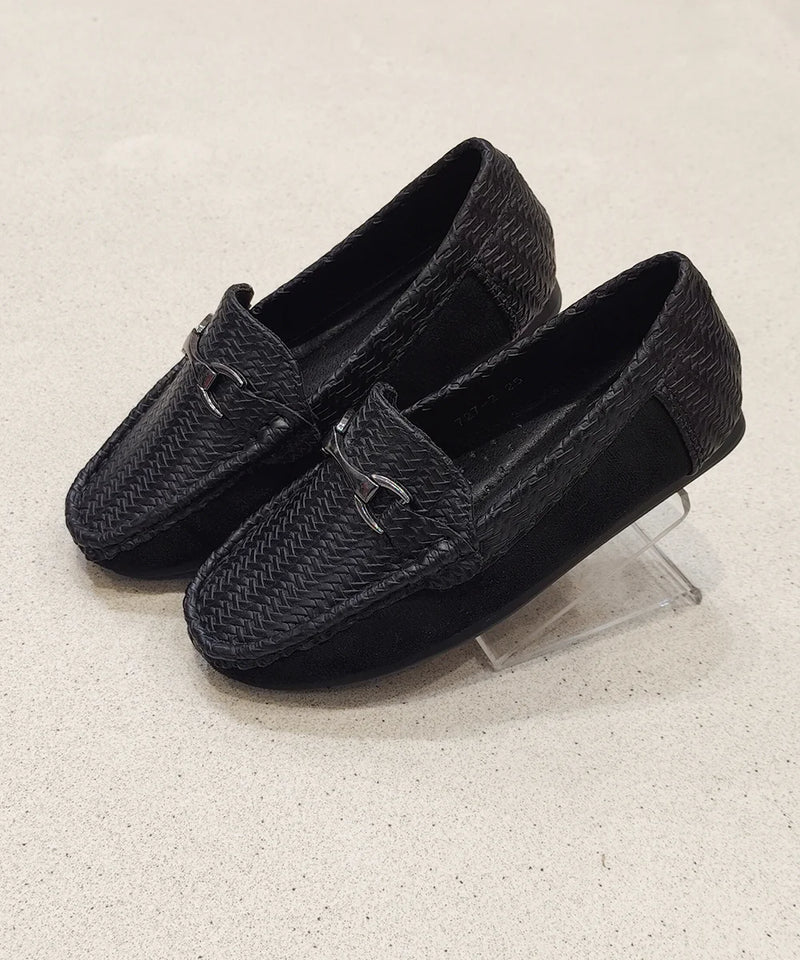 Pair of black loafers with woven texture on a light gray background