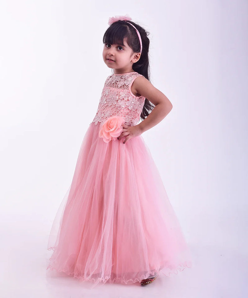 Young girl in a pink dress holding a flower against a white background