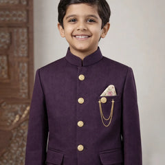 Young boy wearing a purple traditional outfit with gold buttons and a pocket square.