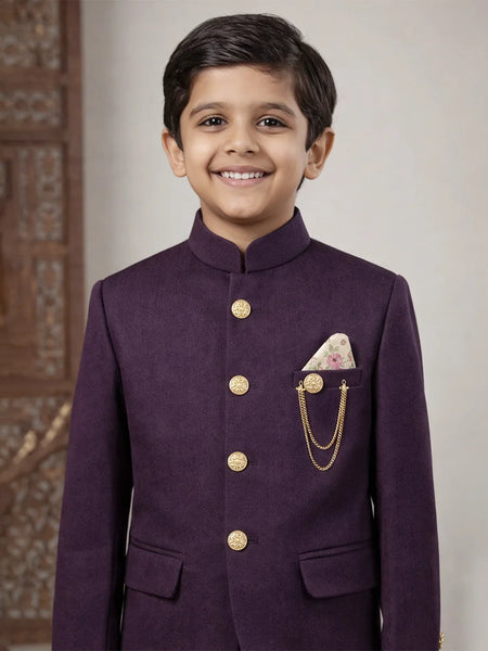 Young boy wearing a purple traditional outfit with gold buttons and a pocket square.