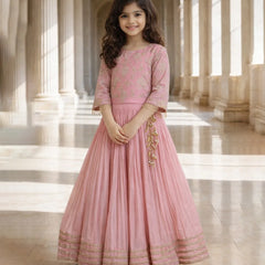 Young girl in a pink traditional outfit standing in a grand hall with columns.