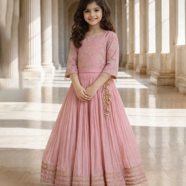 Young girl in a pink traditional outfit standing in a grand hall with columns.